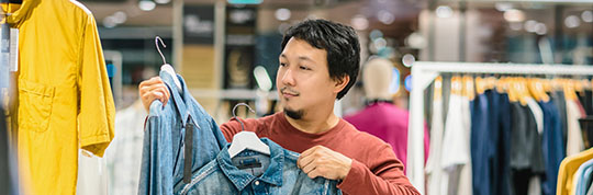 Man with beard choosing clothes in clothing store at shopping center,